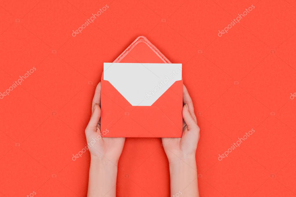 Partial top view of person holding red envelope with blank white card isolated on red