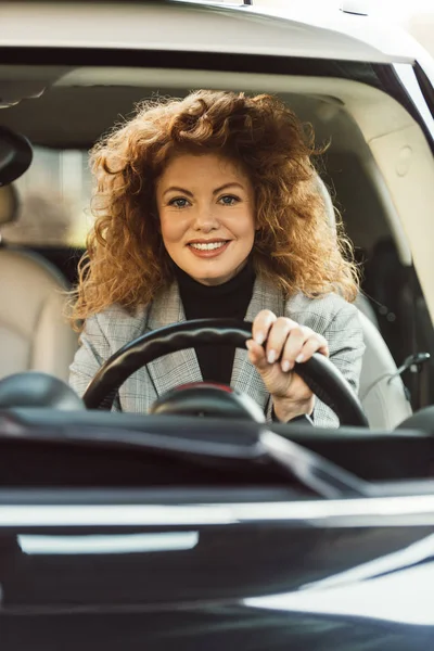 Glimlachend Aantrekkelijke Krullend Roodharige Vrouw Rijdt Auto — Gratis stockfoto