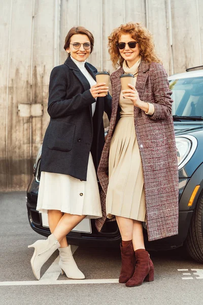 Happy Stylish Women Coats Posing Disposable Coffee Cups Car Urban — Free Stock Photo