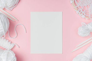 boş kağıt pembe bir arka plan üzerinde beyaz iplik, örgü iğneleri ile düz lay