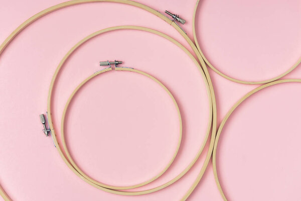 flat lay with wooden embroidery hoops arranged on pink background