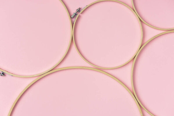 flat lay with wooden embroidery hoops arranged on pink background
