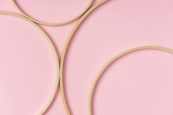 flat lay with wooden embroidery hoops arranged on pink background