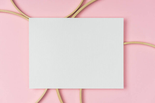 flat lay with wooden embroidery hoops and blank paper arranged on pink background