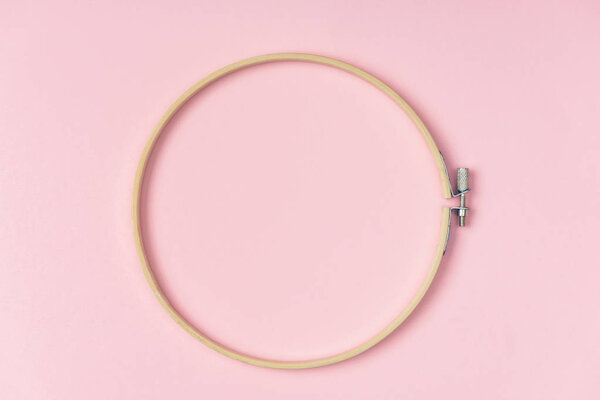 top view of wooden embroidery hoop on pink background