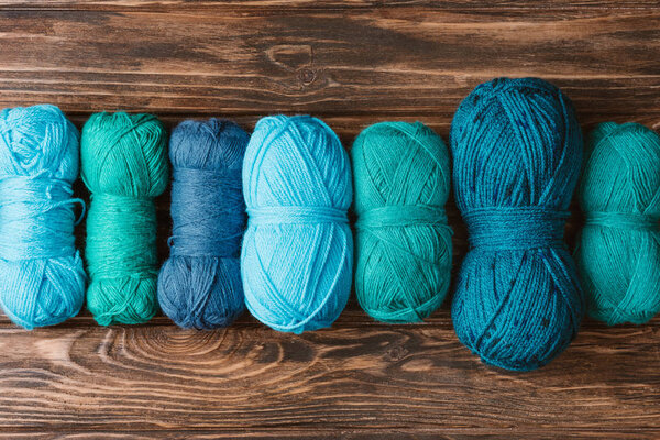 Верхний вид зеленой и синей вязальной пряжи прилипает к деревянной поверхности
