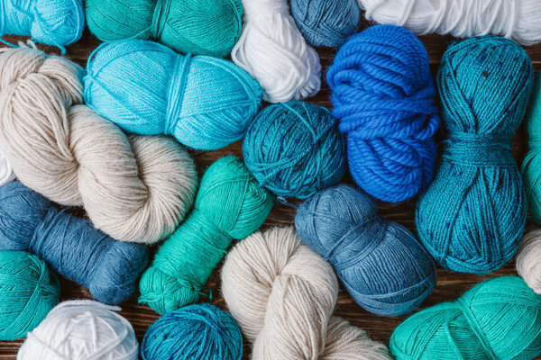 flat lay with arranged blue, white and green yarn clews on wooden tabletop