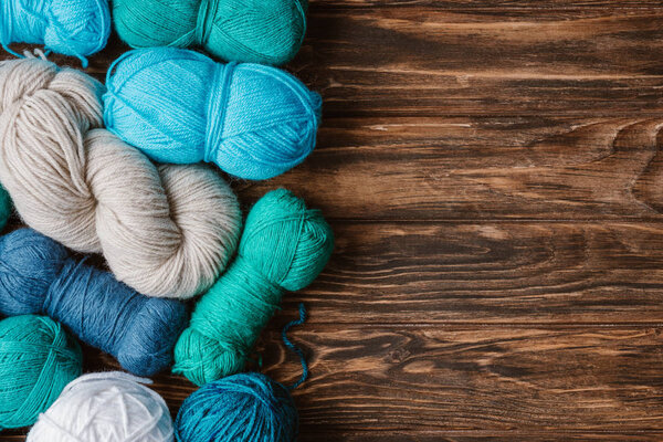 flat lay with arranged blue, white and green yarn clews on wooden tabletop