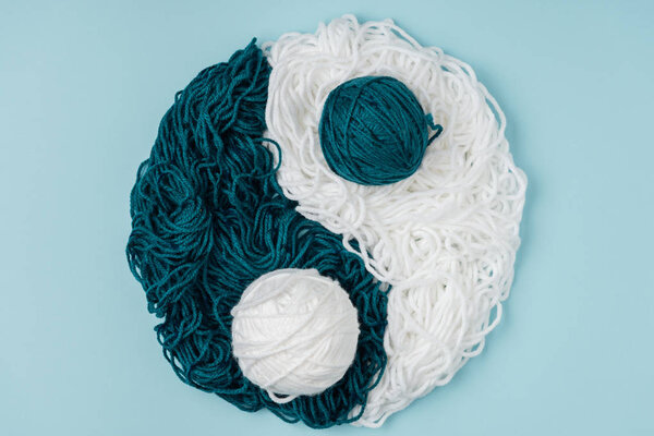 top view of blue and white yarn arranged in yin yang sign on blue background