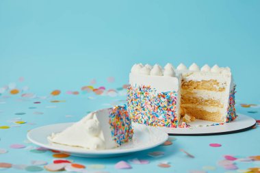 Slice of cake with cut cake on blue background with confetti clipart