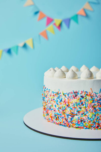 Delicious cake with sugar sprinkles and meringues on blue background
