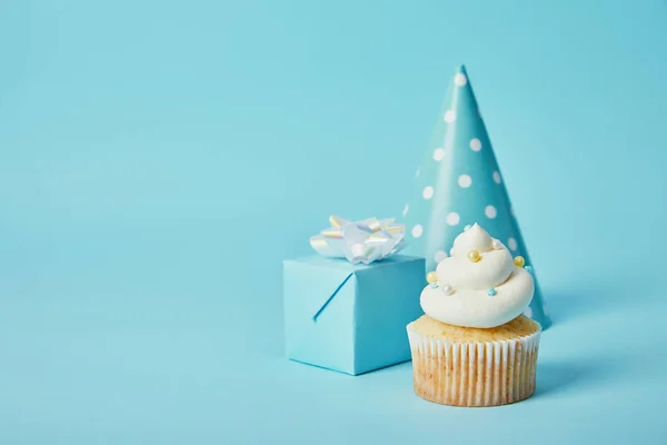 Partyhut Geschenkbox Und Leckerer Cupcake Auf Blauem Hintergrund — Stockfoto