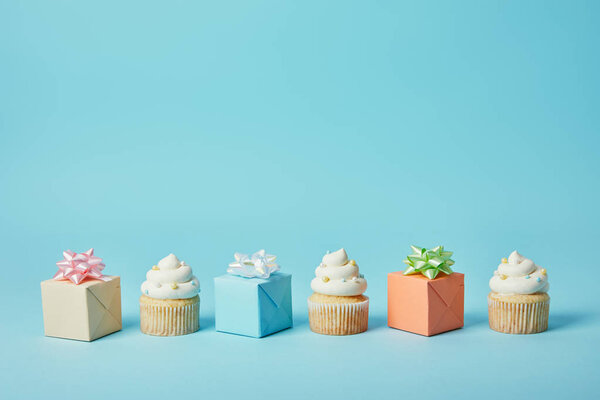 Delicious cupcakes and diffrent gifts on blue background
