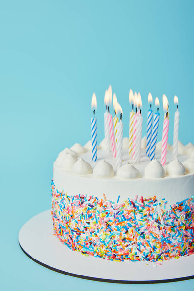 Торт на день рождения с зажженными свечами на синем фоне

