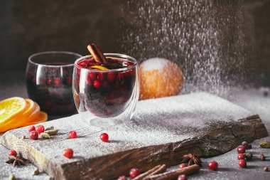 tasty homemade mulled wine with cranberries and falling powdered sugar in kitchen clipart