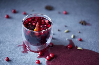 glass of homemade mulled wine with cranberries and orange on tabletop in kitchen clipart