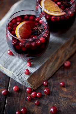 high angle view of glasses of homemade mulled wine with cranberries on wooden stand in kitchen clipart
