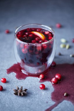 glass of warm mulled wine with cranberries on tabletop in kitchen clipart