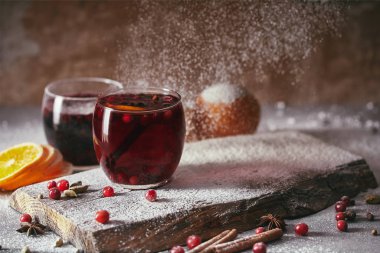 hot homemade mulled wine with cranberries with falling powdered sugar on table in kitchen clipart