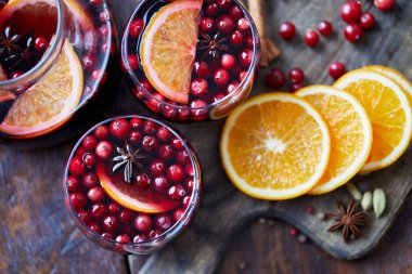 elevated view of homemade mulled wine with cranberries and oranges on table in kitchen clipart