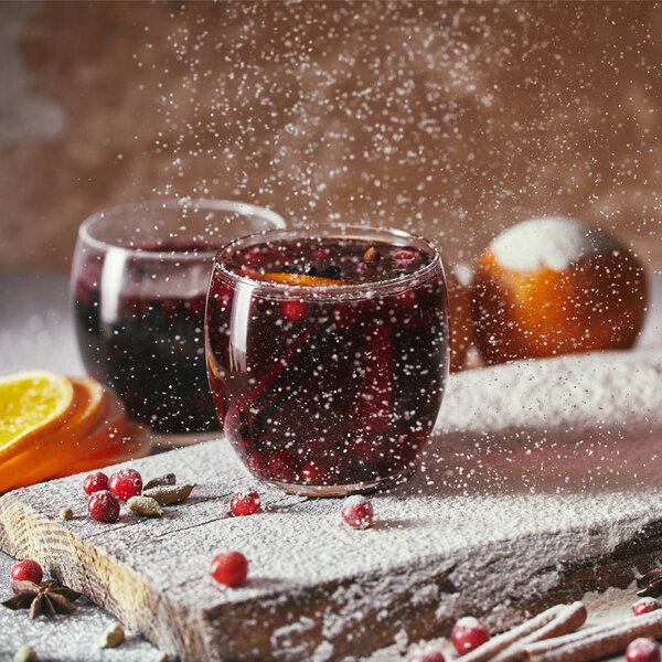 homemade mulled wine with cranberries and falling powdered sugar in kitchen