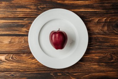 ahşap masa üzerinde kırmızı lezzetli apple ile beyaz plaka üstten görünüm