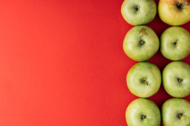 Olgun büyük yeşil elma satır üstten görünüm kırmızı zemin üzerine