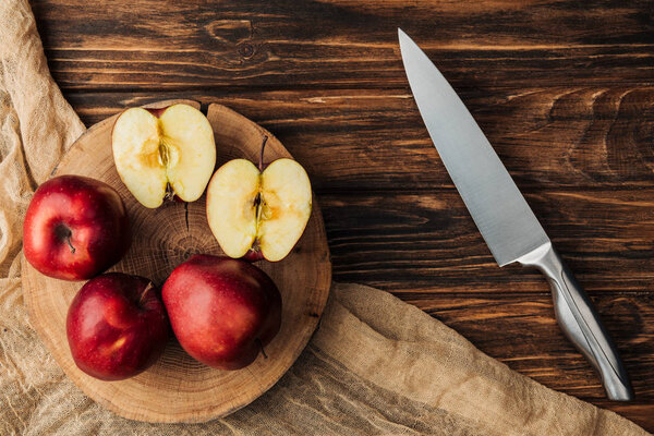 top view of red delicious apples on stump, knife and fabric on wooden table
