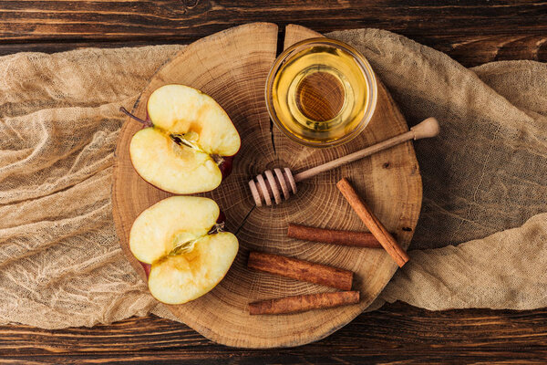 top view of stump with cut apple halves and honey on wooden table