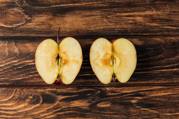 top view of cut ripe apple halves on wooden table