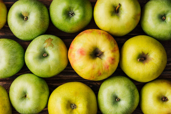 top view of ripe green and golden apples on wooden table