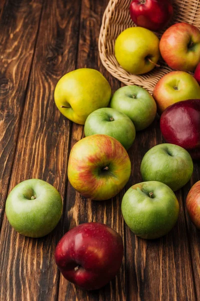 Verstreute Bunte Äpfel Und Weidenkorb Auf Holztisch — Stockfoto