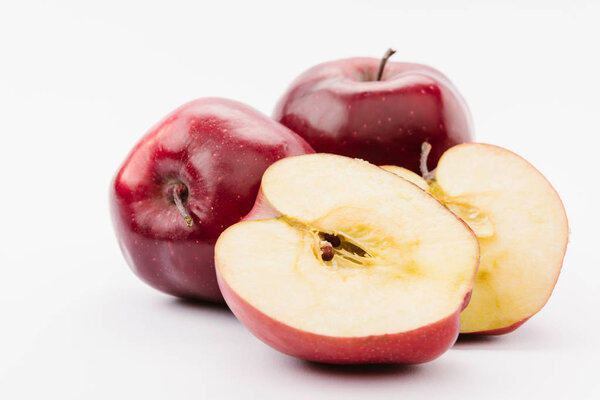 halved and whole tasty red apples on white background