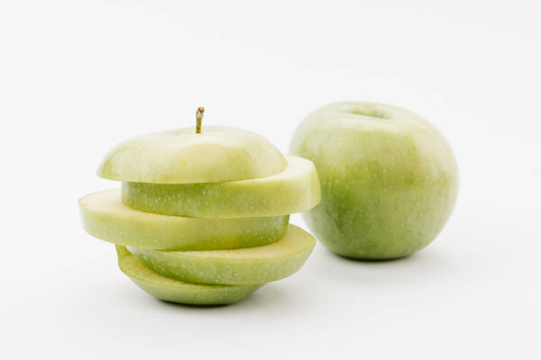 sliced and whole golden delicious apples on white background