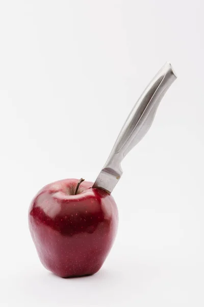 carving knife in whole red delicious apple isolated on white