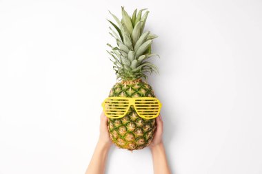 Beyaz arka plan üzerinde güneş gözlüğü ananas tutan kadın görünümünü kırpılmış