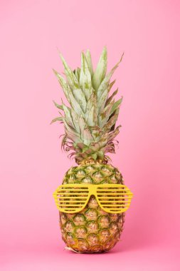 komik ve lezzetli ananas pembe bir arka plan üzerinde güneş gözlüğü