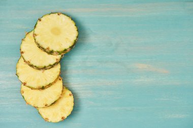 Turkuaz ahşap masa üzerine dilimlenmiş sarı ananas çevrelerin üstten görünüm
