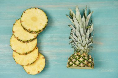Turkuaz ahşap masa üzerine dilimlenmiş daireler ve kesme ananas üstten görünüm
