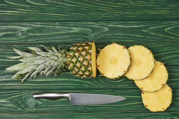 在绿色木桌上可以看到成熟菠萝切片圆圈的顶视图 — 图库照片
