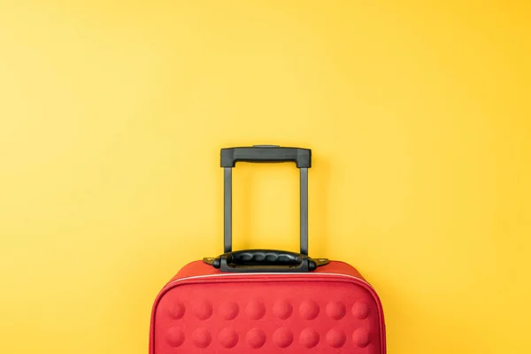 黄色の背景に赤の旅行バッグのトップ ビュー — ストック写真