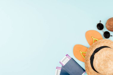 mavi arka plan üzerinde güneş gözlüğü, flip flop, hasır şapka, Hindistan cevizi ve pasaport uçak bileti ile üstten görünüm 
