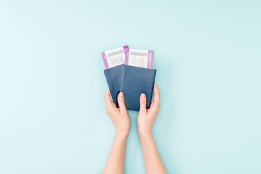 Pasaportlar ve uçak bileti mavi arka plan üzerinde tutan kadın görünümünü kırpılmış 