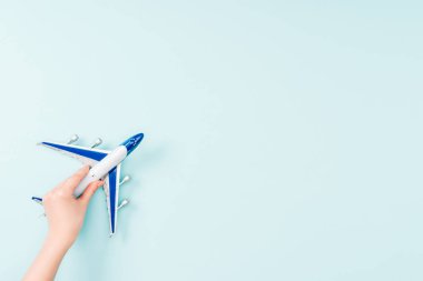 cropped view of woman holding small toy plane on blue background  clipart