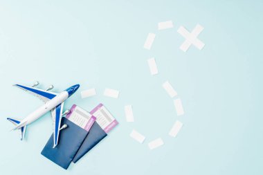 mavi arka plan üzerinde oyuncak uçak, noktalı çizgi, uçak bileti ve pasaport üstten görünüm