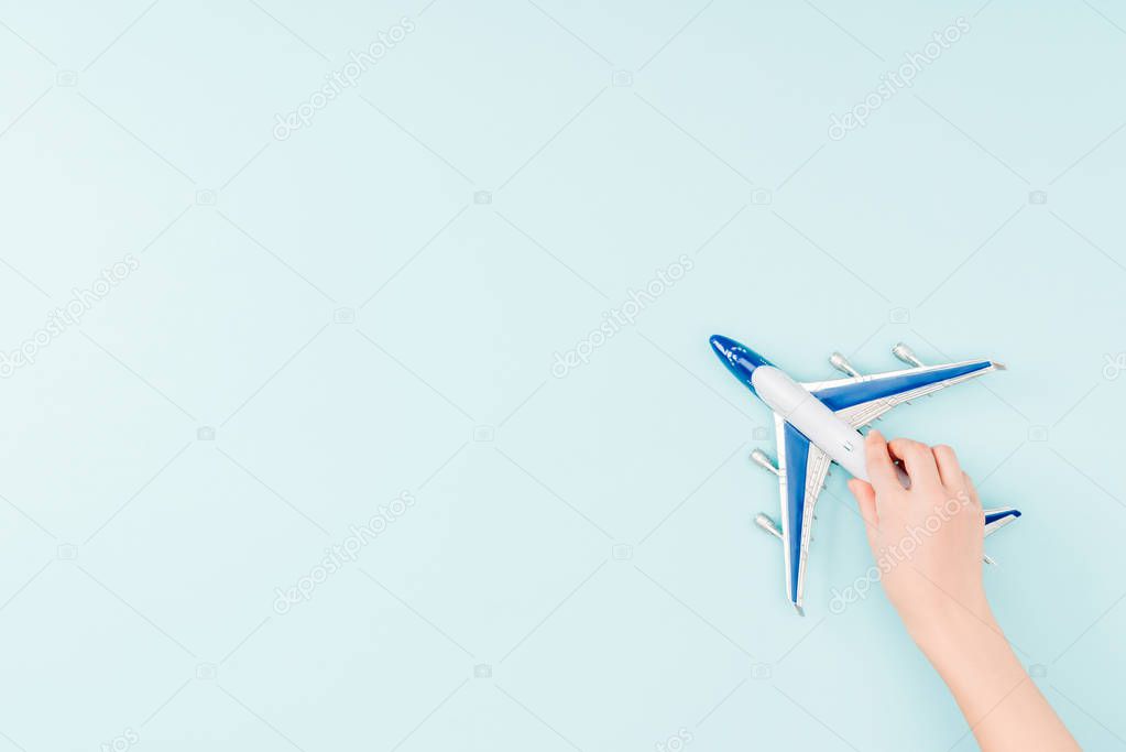 cropped view of woman holding toy plane on blue background 