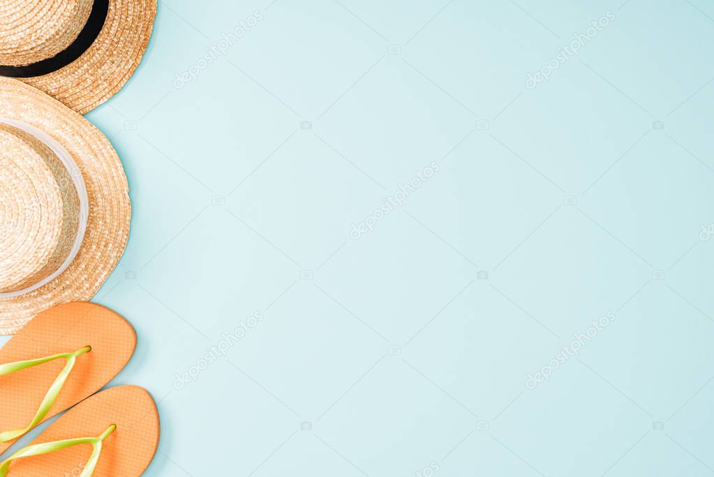 top view of straw hats and flip flops on blue background