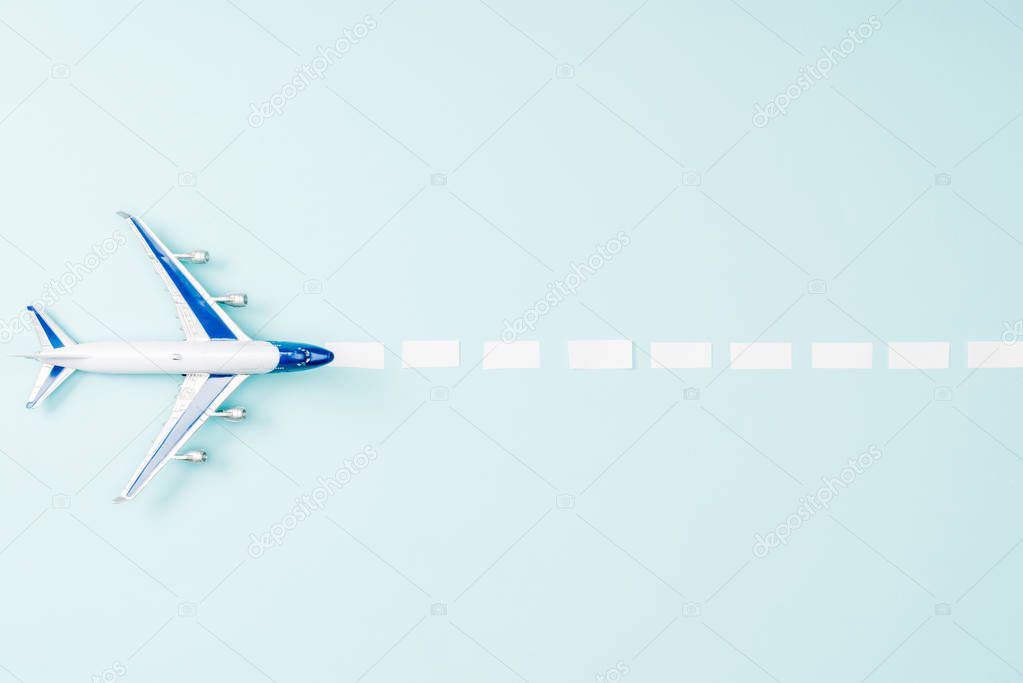 top view of toy plane and dotted line on blue background