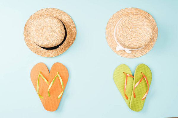 top view of straw hats and flip flops on blue background