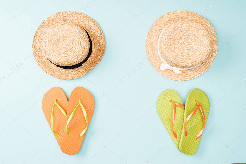 top view of straw hats and flip flops on blue background